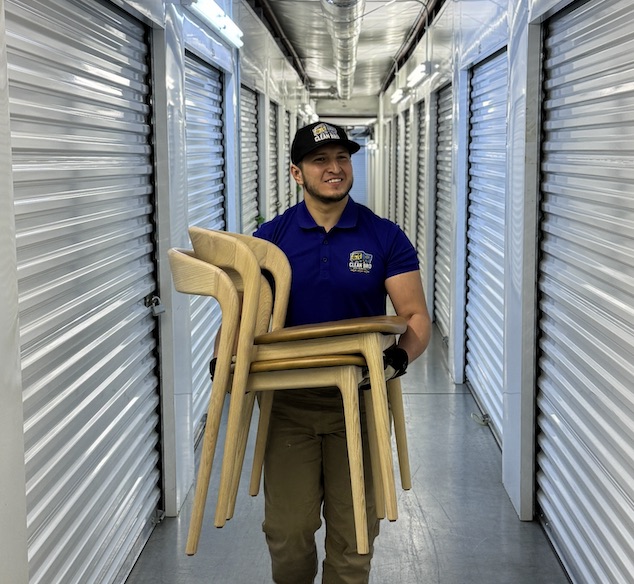 CleanBroServices team member carrying chairs through a storage hallway